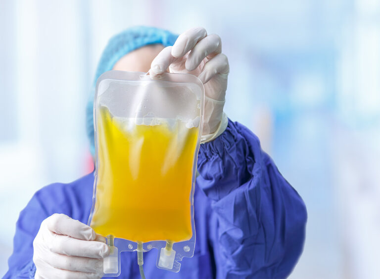 image of a lab worker holding a bag of yellow plasma